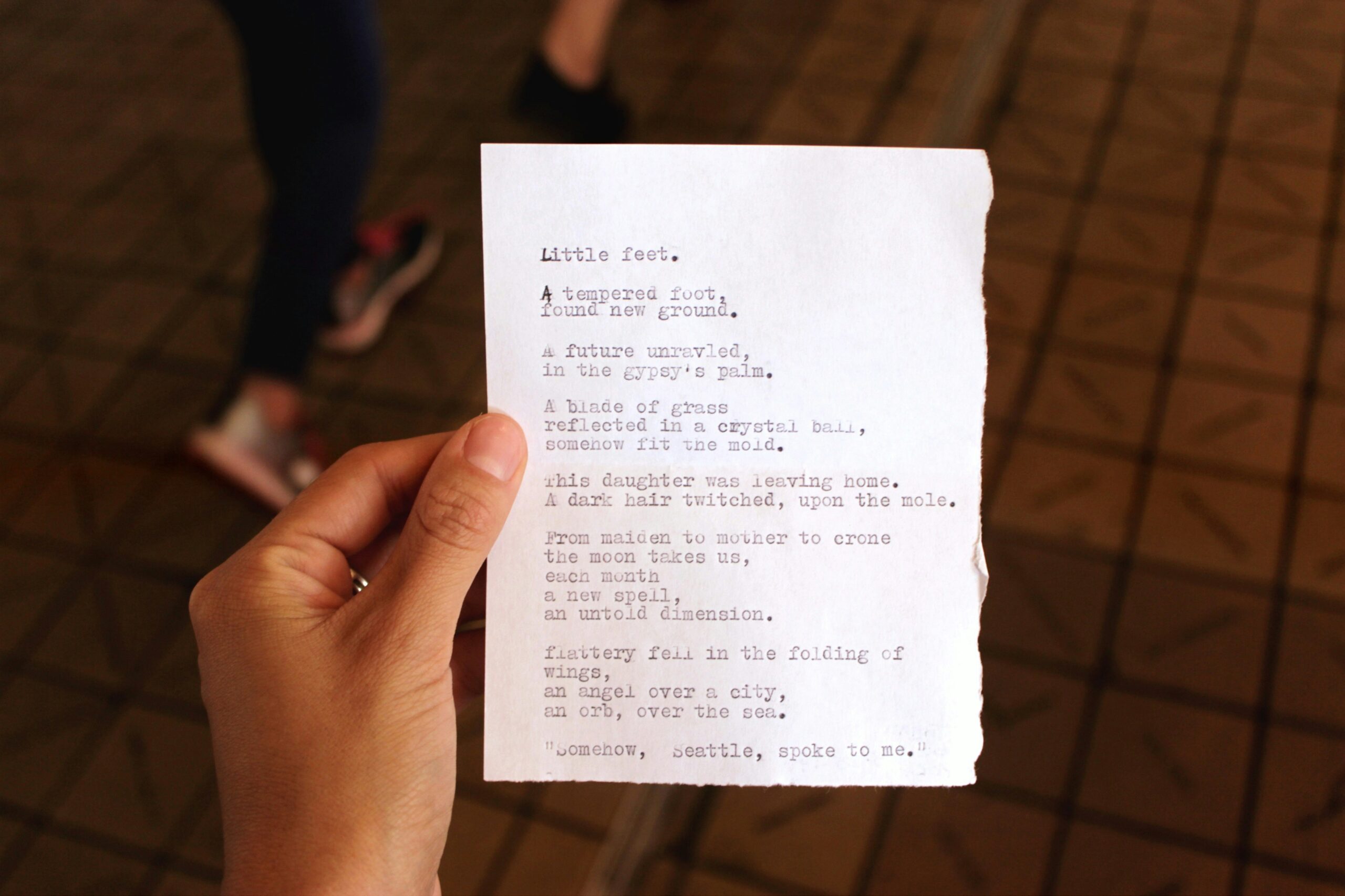 A hand holding out a paper that contains a poem that's using metaphors.